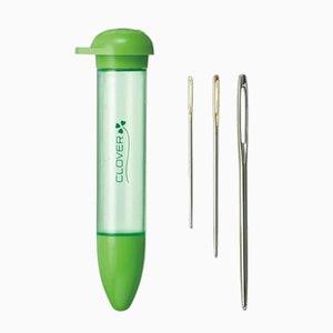 May include: A green plastic container with a clover logo and the word "CLOVER" printed on it. The container holds three silver sewing needles.