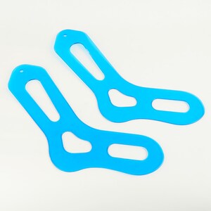 Könnte beinhalten: Zwei blaue, sockengestaltige Schablonen aus Kunststoff zum Nähen von Socken. Die Schablonen sind für die Verwendung mit einer Nähmaschine konzipiert.