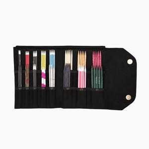 May include: A black fabric roll-up case with a variety of knitting needles in different colors and materials. The needles are organized in rows and secured in place. The case has two snap closures.