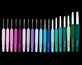 Puede incluir: Un conjunto de ganchillos de diferentes tamaños y colores, dispuestos en fila sobre un fondo negro. Los ganchillos tienen mangos de colores, que van del rosa claro al verde oscuro, con puntas de metal plateado. Las tallas están indicadas en milímetros.