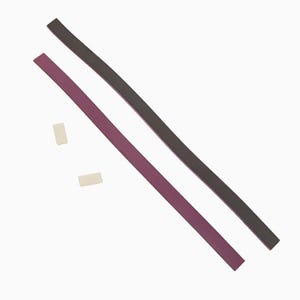 Puede incluir: Dos tiras de tela, una morada y otra negra, con dos pequeños cuadrados adhesivos blancos.