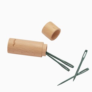 May include: A set of four green wooden needles in a wooden case with a lid. The case is labeled "KnitPro".