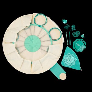 May include: A circular off-white and teal knitting needle case with various knitting tools. The case is open, revealing multiple knitting needles. Additional teal accessories include stitch markers, a needle case, and a small pouch with a floral design.