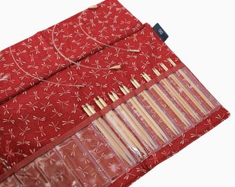 May include: A red fabric case with a dragonfly pattern holds a set of 15 pairs of bamboo knitting needles. The case has a clear plastic pocket for each pair of needles. The case is open and the needles are visible.