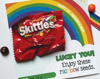 Op de afbeelding: Een kaart met een regenboogachtergrond en de tekst "Happy St. Patrick's Day!"  Een zakje Skittles snoep ligt op de kaart met de tekst "Lucky You! Enjoy these rainbow seeds."  De kaart is ondertekend met "From: Hailey".