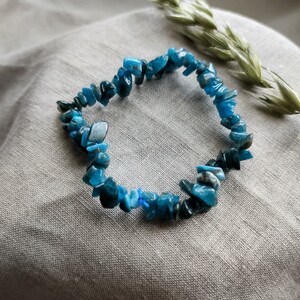 Op de afbeelding: Een blauwe edelsteen chip armband gemaakt met kleine, onregelmatige stukjes blauwe apatiet. De armband is geregen op elastisch koord en is ongeveer 18 cm lang.
