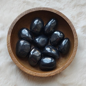 Peut inclure: Un bol de pierres d'obsidienne noire roulées. Les pierres sont lisses et polies, et elles ont une couleur noire profonde et riche.