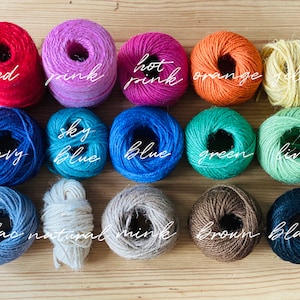 May include: A collection of colorful twine spools in shades of red, pink, hot pink, orange, yellow, navy, sky blue, blue, green, lime, lilac, natural, mink, brown, and black. Each spool has the color name written in cursive.