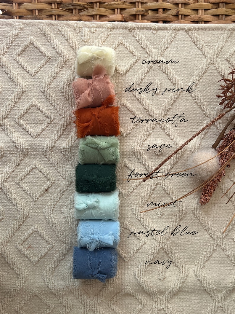 May include: A stack of fabric scraps in various colors, including cream, dusty pink, terracotta, sage, forest green, mint, pastel blue, and navy. The fabric scraps are arranged vertically on a white textured surface.