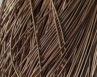 May include: A close-up of a pile of gold-colored metal wire. The wire is arranged in a random pattern, creating a textured and abstract look.