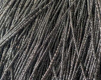 May include: A close-up of a bundle of black and silver metallic cord. The cord is twisted and has a shiny finish.