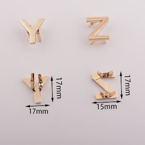 May include: Gold metal letter charms in the shape of the letters Y, Z, and S. The charms are 1.7 inches tall and 1.7 inches wide. The S charm is 1.5 inches wide.