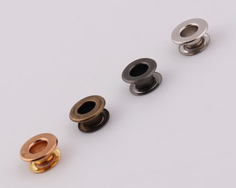 Può includere: Quattro occhielli metallici in diverse finiture: argento, nero, bronzo e oro. Gli occhielli sono rotondi con un bordo rialzato e un foro al centro.