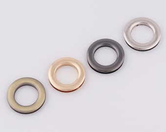 May include: Four metal grommets in different finishes: gold, silver, black, and antique brass. The grommets are round with a hole in the center.