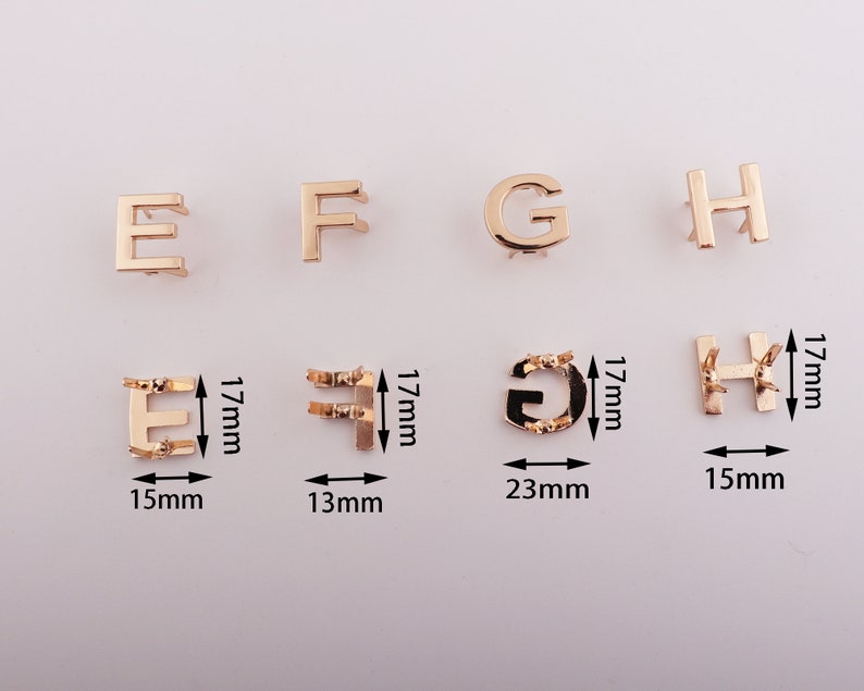 May include: Gold-toned metal letter charms in the shape of the letters E, F, G, and H. The charms are approximately 1.7 cm tall and range in width from 1.3 cm to 2.3 cm.