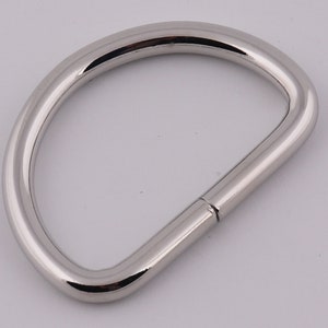 Pu&ograve; includere: Un anello a D in metallo argentato con una finitura liscia e lucida. L'anello &egrave; aperto da un lato e chiuso dall'altro.