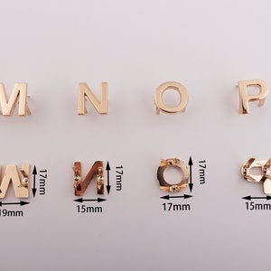 May include: Gold metal letters M, N, O, P, W, and a circle, each with a small hole at the top. The letters are approximately 1.5 inches tall and the circle is approximately 1.5 inches in diameter.