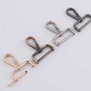 May include: Four metal swivel clasps in different finishes: gold, silver, antique brass, and black. Each clasp has a hook and a D-ring.