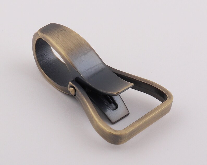 May include: Antique brass swivel trigger snap hook. The hook is open and ready to be attached to a strap, leash, or other item.