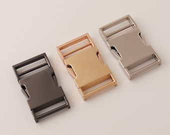 May include: Three metal clasps in different finishes: silver, gold, and black. The clasps are rectangular with a buckle and two loops.