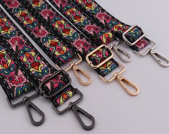 Può includere: Quattro cinturini in tessuto con motivi colorati e fibbie metalliche. I cinturini sono neri con disegni floreali rosa, gialli, blu e verdi. Le fibbie sono argentate, dorate e nere.