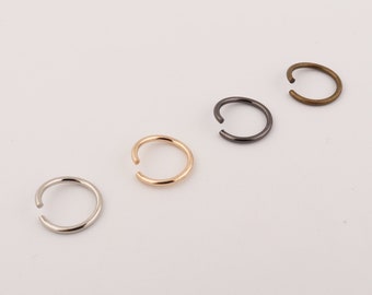 May include: Four different colored metal nose rings. The rings are silver, gold, black, and bronze.
