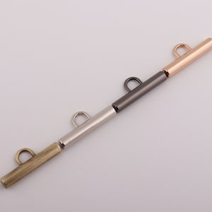 May include: Four metal bar closures in different finishes: gold, gunmetal, silver, and antique brass. Each bar has a loop at one end for attaching to a strap or other item.