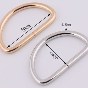 May include: Two metal D-rings, one gold and one silver. The gold ring is 50mm in diameter and the silver ring is 30mm in diameter. Both rings are 4.8mm wide.