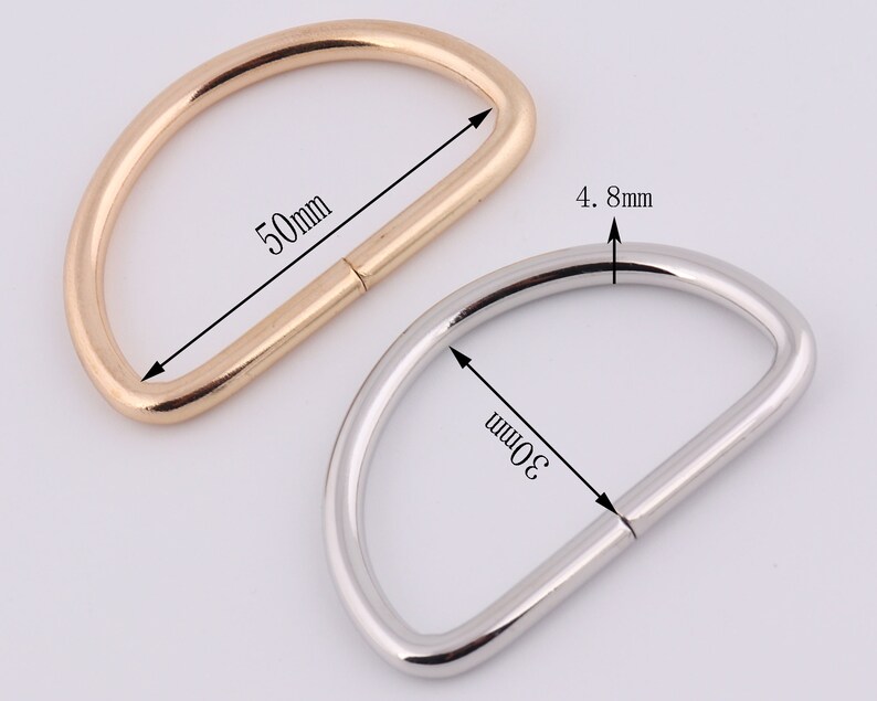 May include: Two metal D-rings, one gold and one silver. The gold ring is 50mm in diameter and the silver ring is 30mm in diameter. Both rings are 4.8mm wide.