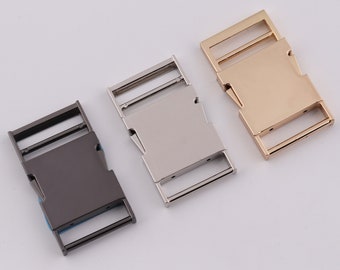 May include: Three metal belt buckles in different colors: black, silver, and gold. The buckles are all the same size and shape, with a rectangular design and a smooth finish.