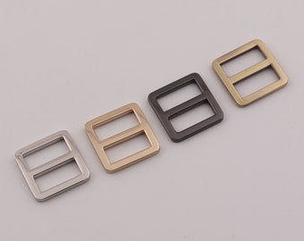 May include: Four metal square-shaped buckles with a double-bar design. The buckles are in silver, gold, black, and bronze.