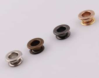 Può includere: Quattro occhielli metallici in diverse finiture: oro, nero, bronzo e argento. Gli occhielli sono rotondi con un foro al centro e un bordo rialzato attorno al bordo.