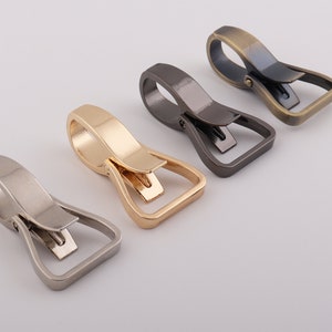 May include: Four metal swivel hooks in different finishes: silver, gold, bronze, and black. The hooks are designed for attaching to bags, belts, or other items.