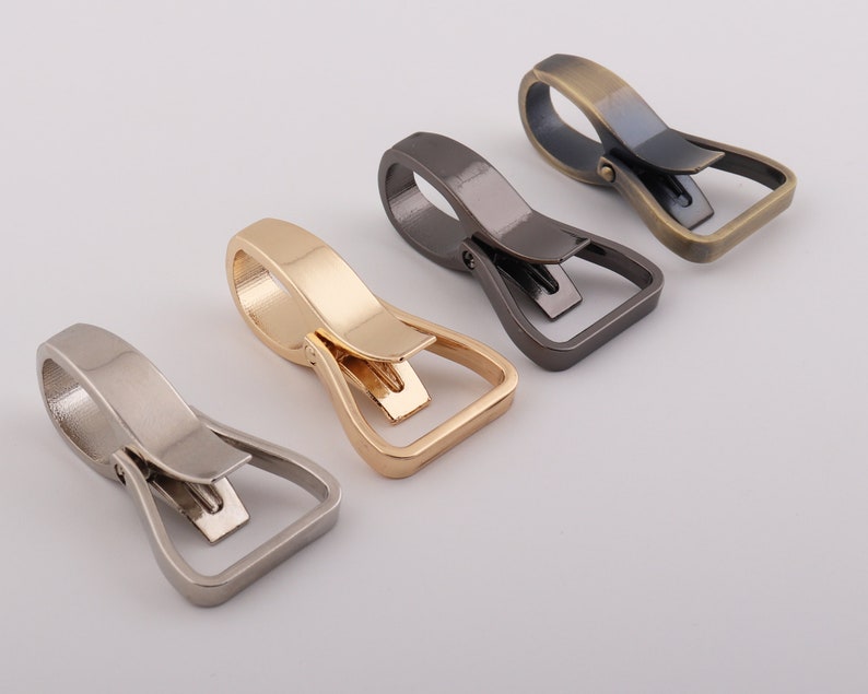 May include: Four metal swivel hooks in different finishes: silver, gold, bronze, and black. The hooks are designed for attaching to bags, belts, or other items.