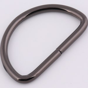 May include: A black metal D-ring with a smooth finish. The ring is open on one side and has a closed loop on the other.