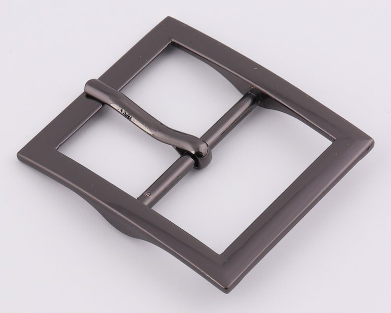 May include: A black metal belt buckle with a rectangular shape and a smooth, slightly curved surface.