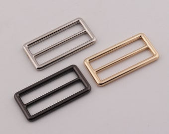 May include: Three metal rectangular buckles in silver, gold, and black.