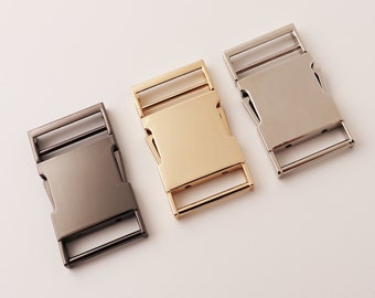 May include: Three metal buckles in different finishes: black, gold, and silver. The buckles are rectangular with a smooth surface and two holes on each side.