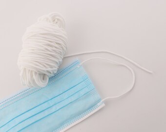 May include: A blue surgical face mask with white elastic ear loops. The ear loops are bundled together and ready to be used.