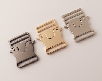 May include: Three metal slider buckles in different finishes: silver, gold, and black. The buckles are designed for straps or belts.