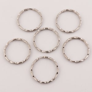 May include: Six silver key rings with a textured finish. The key rings are all the same size and shape.