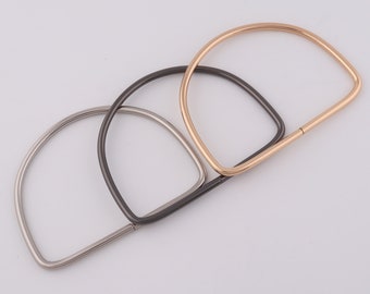 May include: Three metal bag handles in different finishes: gold, silver, and black. The handles are D-shaped and have a straight bar connecting the two ends.