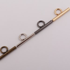 以下が含まれることがあります： 金、銀、ガンメタル仕上げの金属製ジュエリーパーツの詰め合わせ。バーやリングなど。コンポーネントは直線的に配置され、さまざまな色と質感が示されています。ジュエリー作りに最適です。