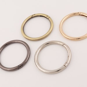 May include: Four metal key rings in different finishes: gold, silver, black, and rose gold. Each ring has a spring-loaded clasp.