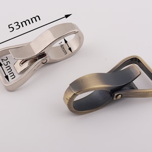 May include: Two metal swivel clasps, one silver and one antique brass. The silver clasp measures 2.5 inches by 5.3 inches. The antique brass clasp measures 2.5 inches by 5.3 inches.
