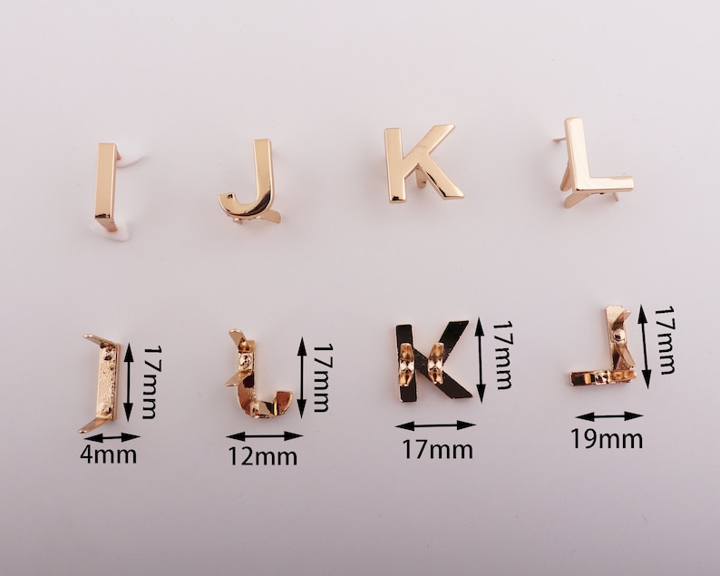 May include: Gold-colored metal letter charms in the shapes of I, J, K, and L. The charms are approximately 1.7 cm tall and 1.7 cm wide. The charms are shown on a white background.