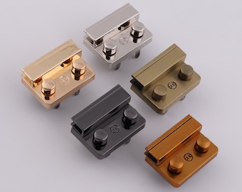May include: Five different colored metal clasps with two round knobs. The clasps are in silver, gold, bronze, black, and copper.
