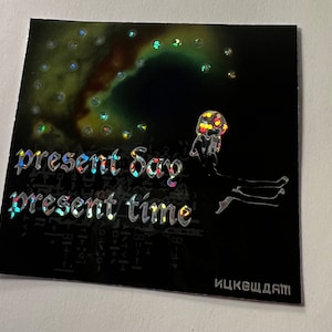 May include: Black square with holographic text that reads "present Say present time". The image features a colorful illustration of a figure with a jellyfish-like head and a dark background with a nebula-like design.
