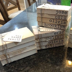 May include: A set of six wooden blocks stacked on top of each other, each block has a name printed on it. The names are: Jose, Cara, Olivia, Brooklyn, Eric, and Ellicott.  Another set of six wooden blocks stacked on top of each other, each block has a name printed on it. The names are: Matt, Lisa, Katie, Mackenzie, Chris, Emily, Willow, and Cooper. A third set of wooden blocks stacked on top of each other, each block has a name printed on it. The names are: Our Happy Family.