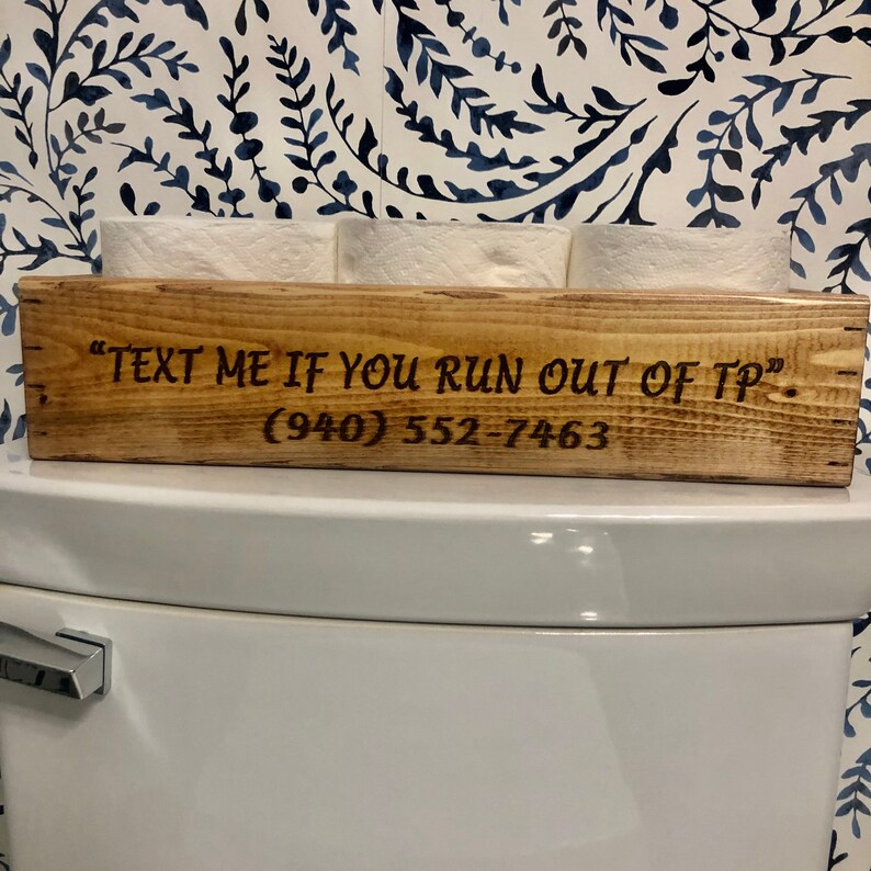 Peut inclure: Porte-papier toilette en bois avec le texte "Text me if you run out of TP" et le num&eacute;ro de t&eacute;l&eacute;phone (940) 552-7463.
